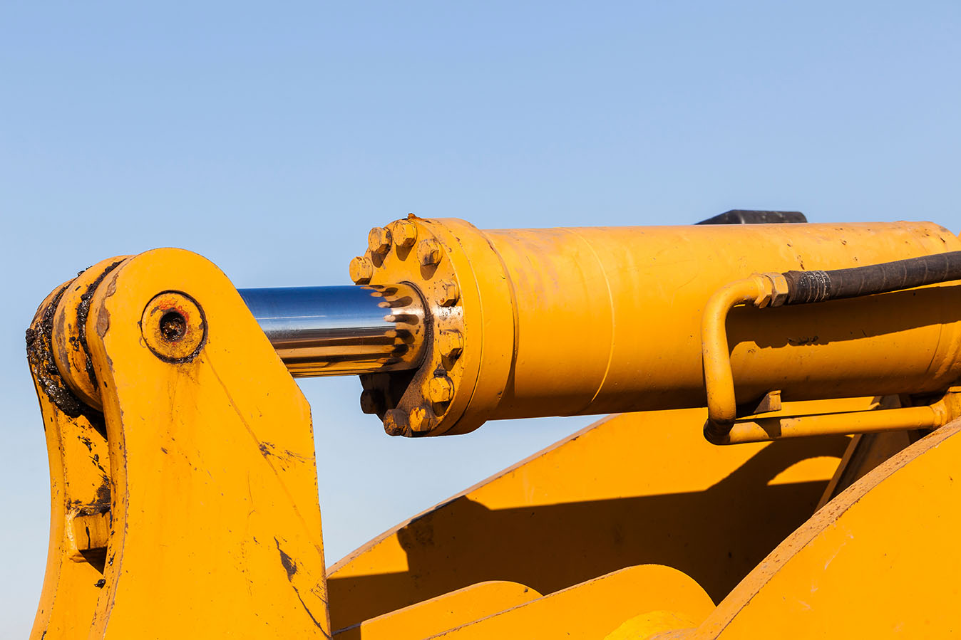 Hydraulic oil power closeup cyclinder ram link pin oil pipe fittings on industrial earthworks machine.